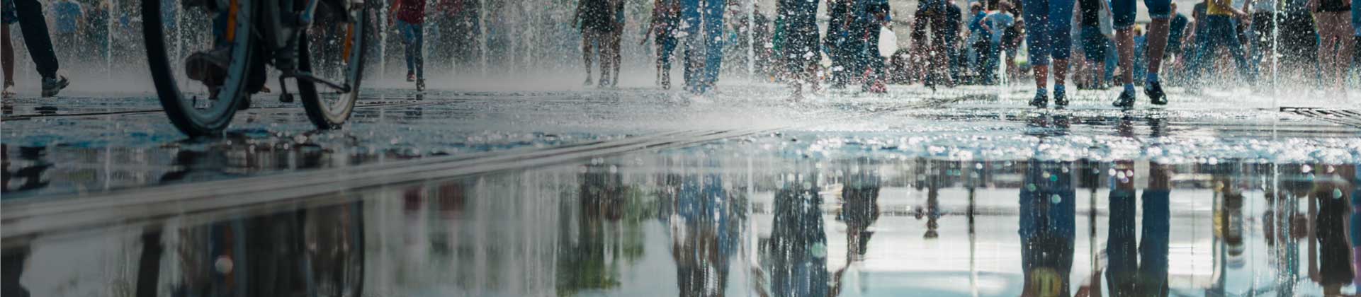 Reflections on a busy street showing people walking and biking through the city