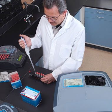 Scientist using Hach spectrophotometer and reagents for laboratory water analysis