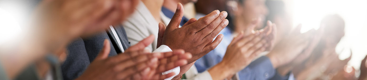 A group of hands with diverse skin tones joining in the center of a circle